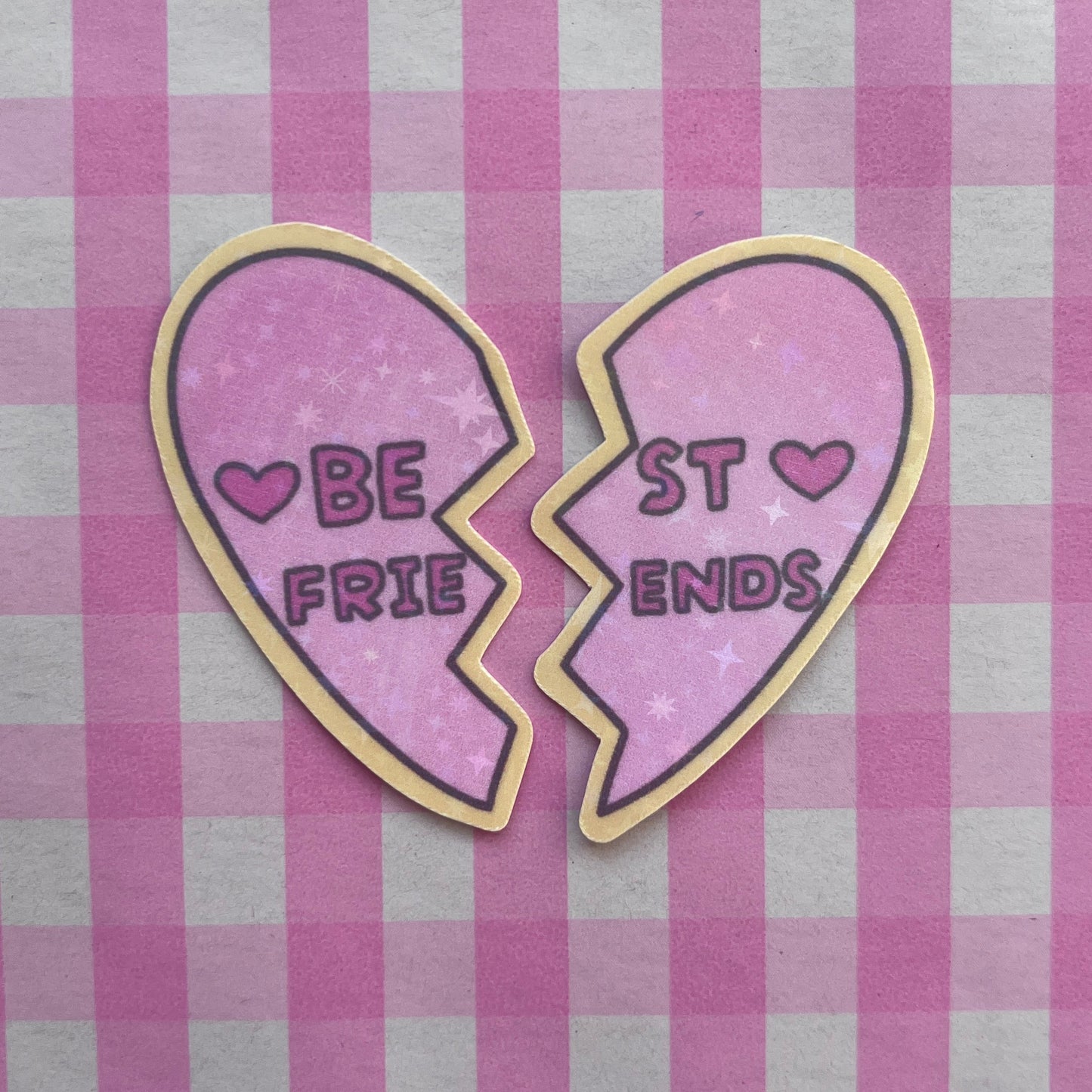 Two half-heart-shaped stickers with 'Be Friends' and 'Best Ends' text on a pink and white checkered background.
